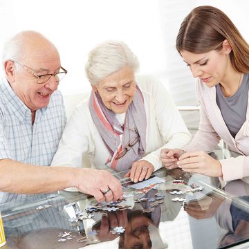Pensionisten und Frau beim Zusammenbauen eines Puzzles.