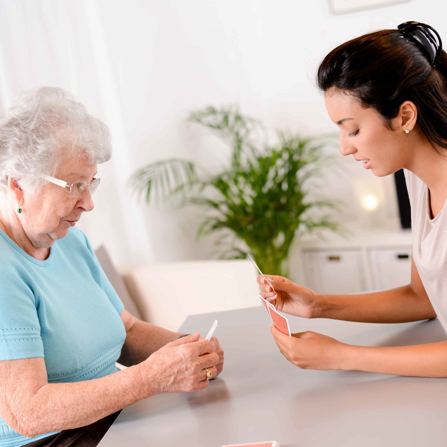 Eine Pflegerin spielt Karten mit einer Klientin.